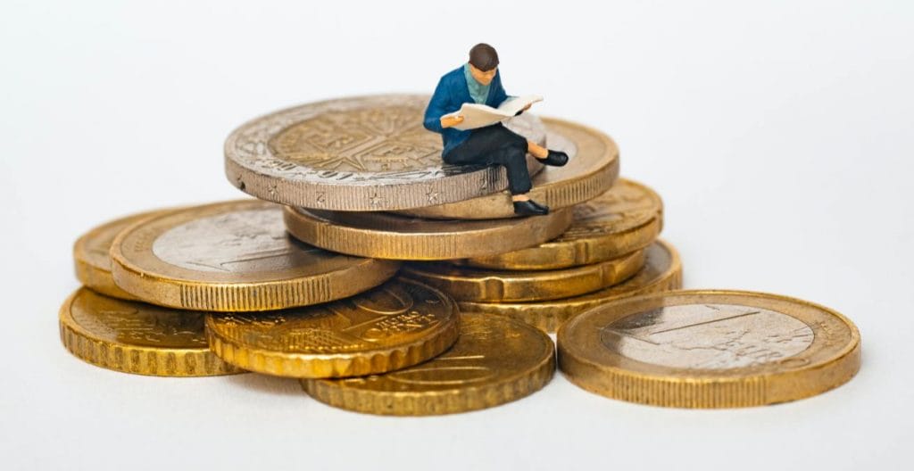 miniature figure sat on top of pile of coins as proxy for how do blogs and vlogs make money